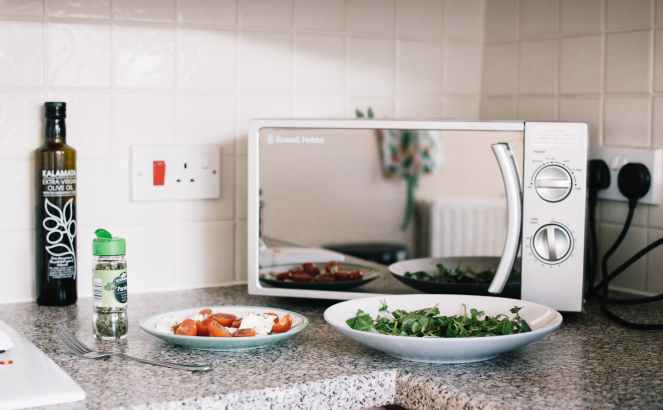 two white ceramic plates near microwave on counter top