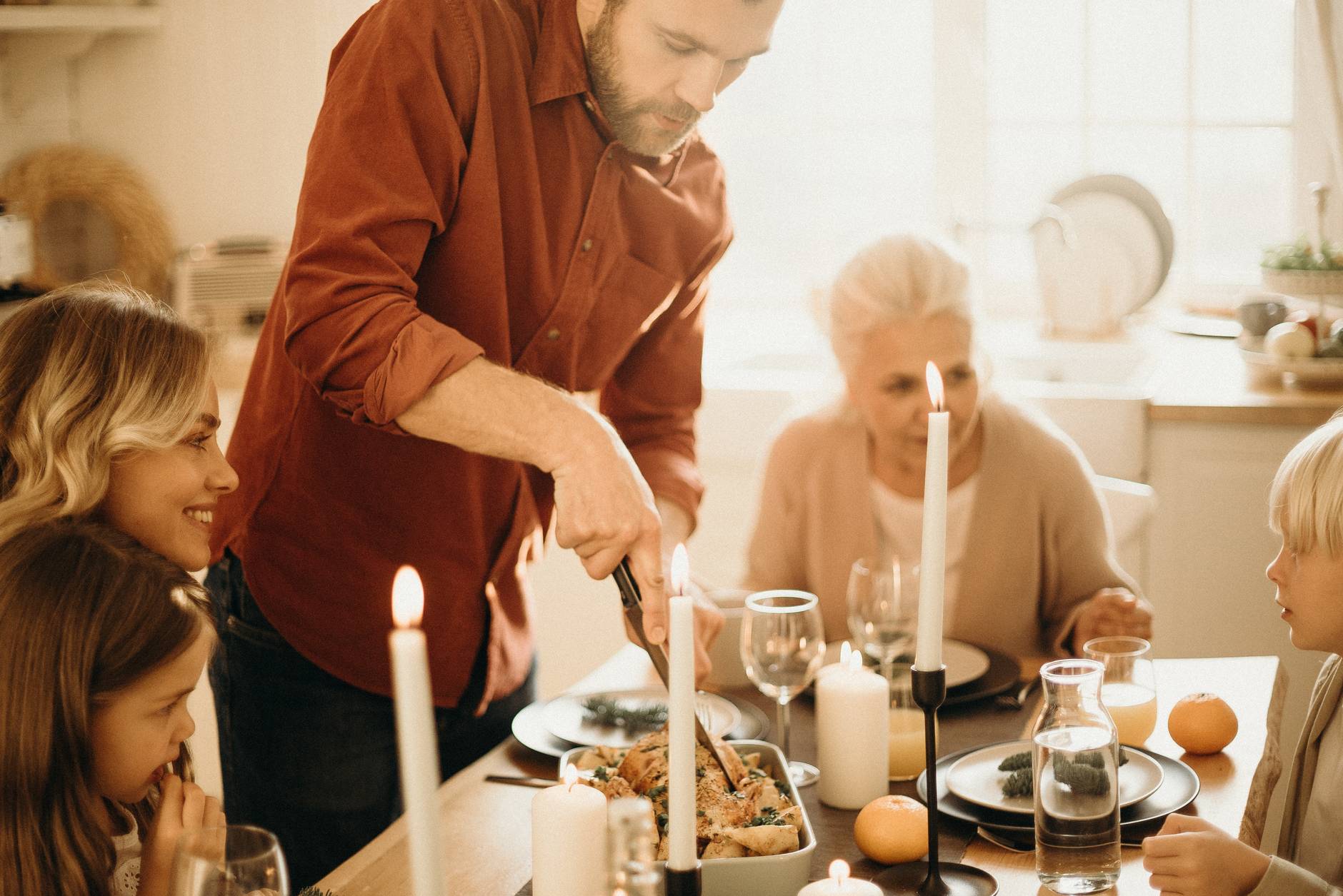 selective focus photography of man preparing food beside smiling women and kids